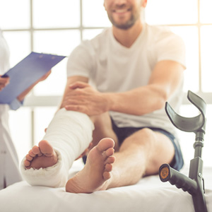 Man with a casted leg and crutches talking to a doctor about an injury while off the clock in Florida workers' compensation law
