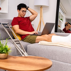 Injured worker with a leg cast working from home for Florida injury claims.